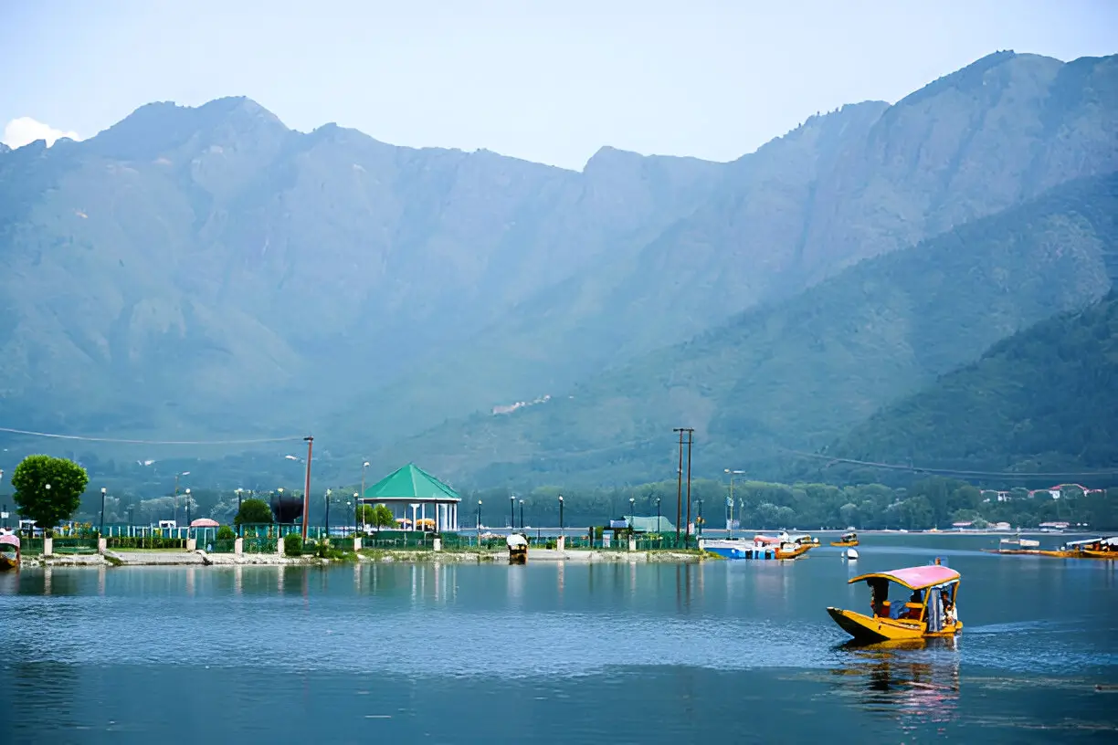 Romantic Shikara ride on Dal Lake, Srinagar, with a couple enjoying serene waters and Himalayan views, part of Kashmir Nirvana’s Luxury Kashmir Honeymoon Package.