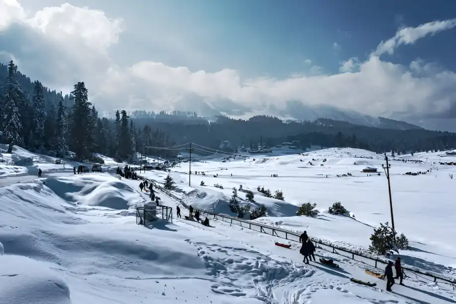 Romantic couple in Gulmarg’s snowy winter landscape, enjoying a honeymoon with Himalayan views, part of Kashmir Nirvana’s Luxury Kashmir Honeymoon Package.