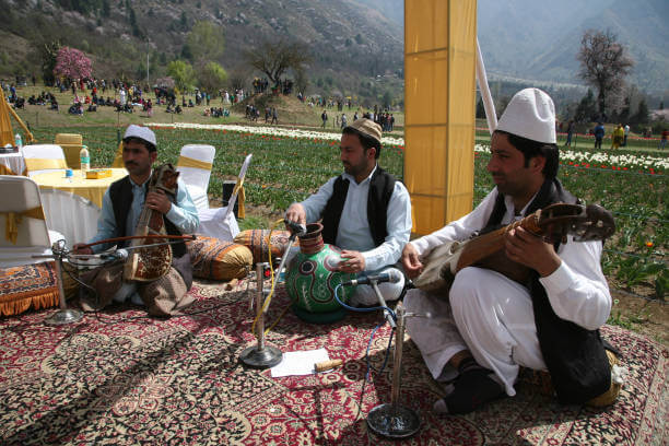 Sufi singer performing qawwali on a stage surrounded by rainbow tulips at Asia's largest Tulip Garden in Kashmir.